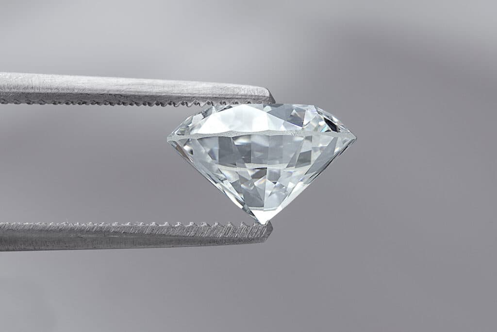 gem cutting styles - Diamond cut in the classic Round Brilliant style held by tweezers
