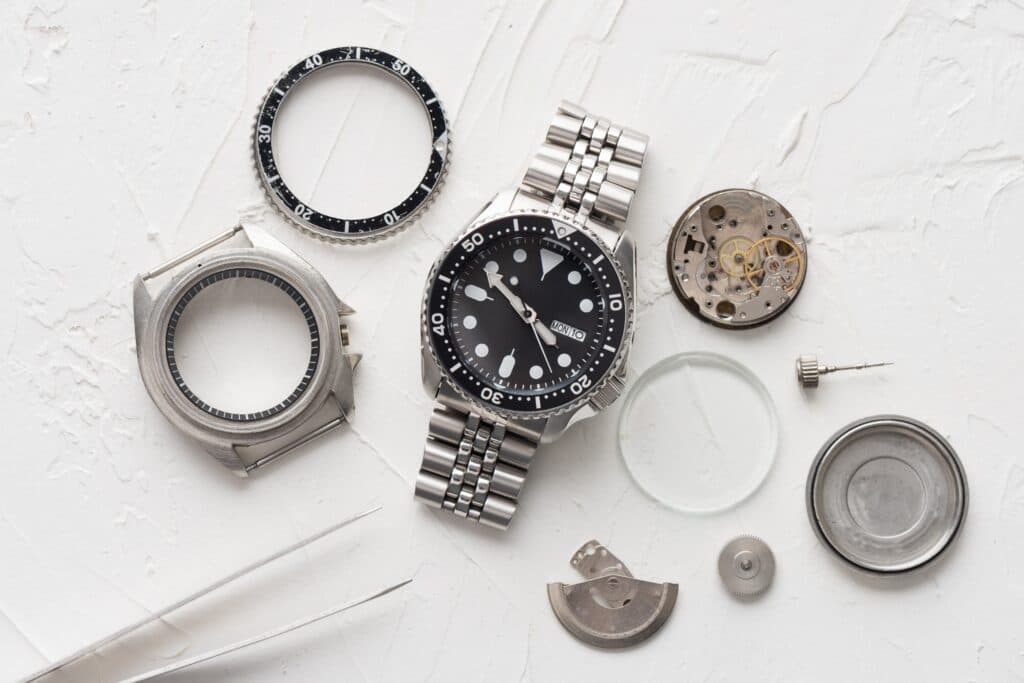 hand watch next to watch spare parts including sapphire glass showcasing sapphire role in watchmaking technology