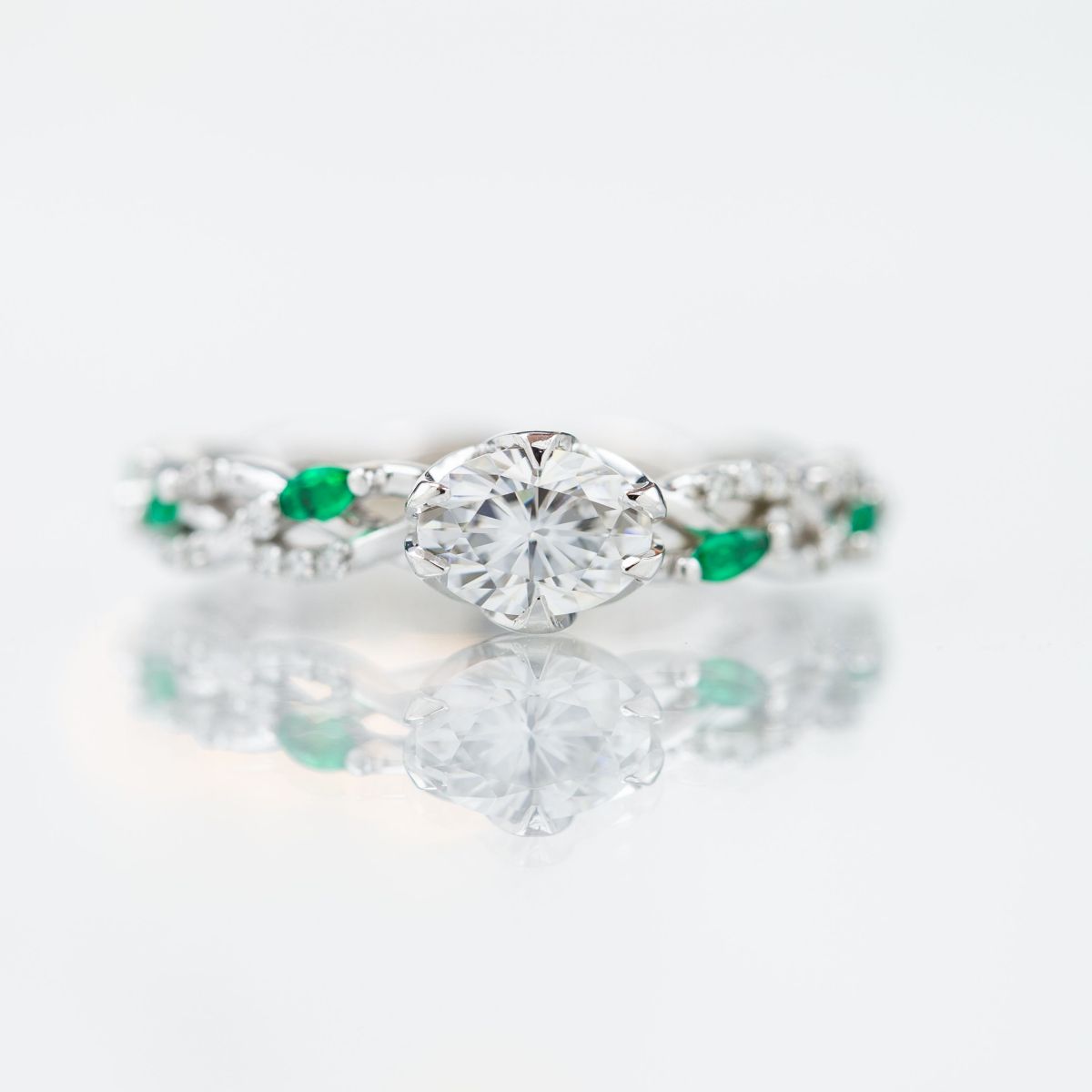 oval moissanite with emerald accents