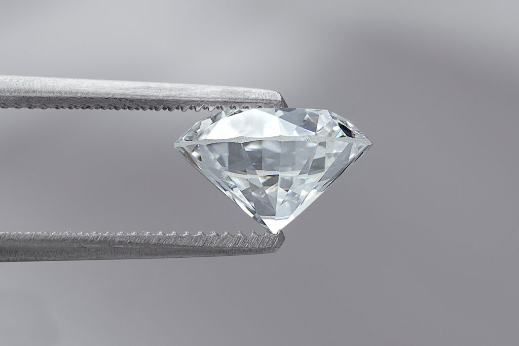 gem cutting styles - Diamond cut in the classic Round Brilliant style held by tweezers